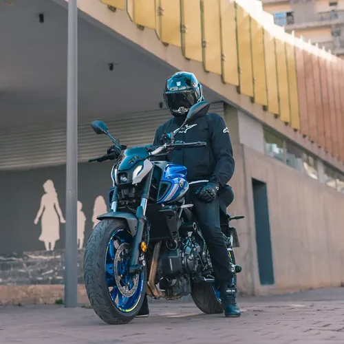 Motorrijder met volledige beschermende kleding staat stil naast zijn lesmotor voor aanvang van de AVB training