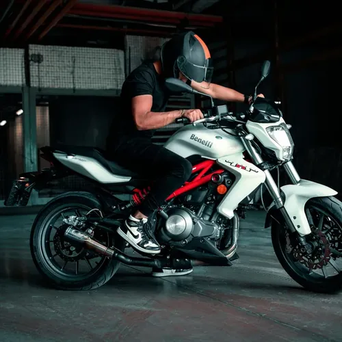 Motorrijder op een witte Benelli naked bike in een garage, illustratie bij de kosten van een motorrijbewijs