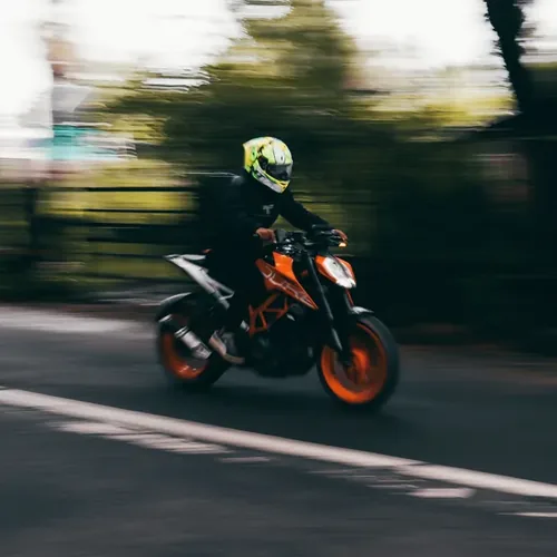 Motorrijder met fluorescerende helm op een oranje naked bike tijdens een intensieve spoedcursus motorrijbewijs