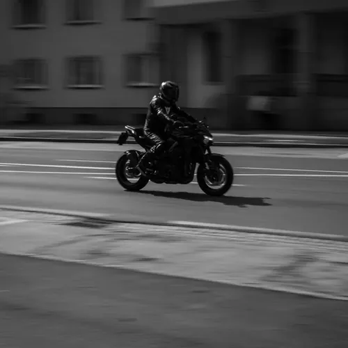 Motorrijder in zwart leer rijdt door de stad, zwart-witbeeld dat de vrijheid van het motorrijbewijs A weergeeft